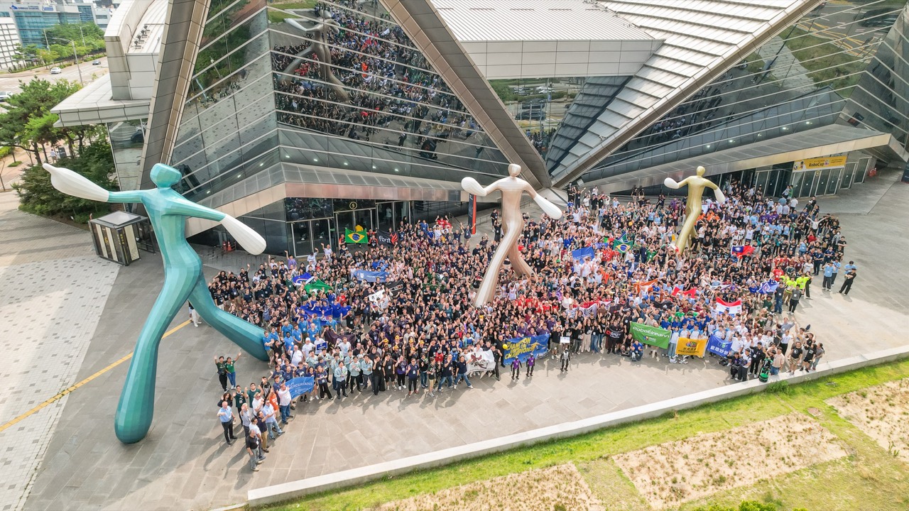 Aerial view of every RoboCup 2026 participant — thousands of people with team flags from 43 countries outside the Incheon venue